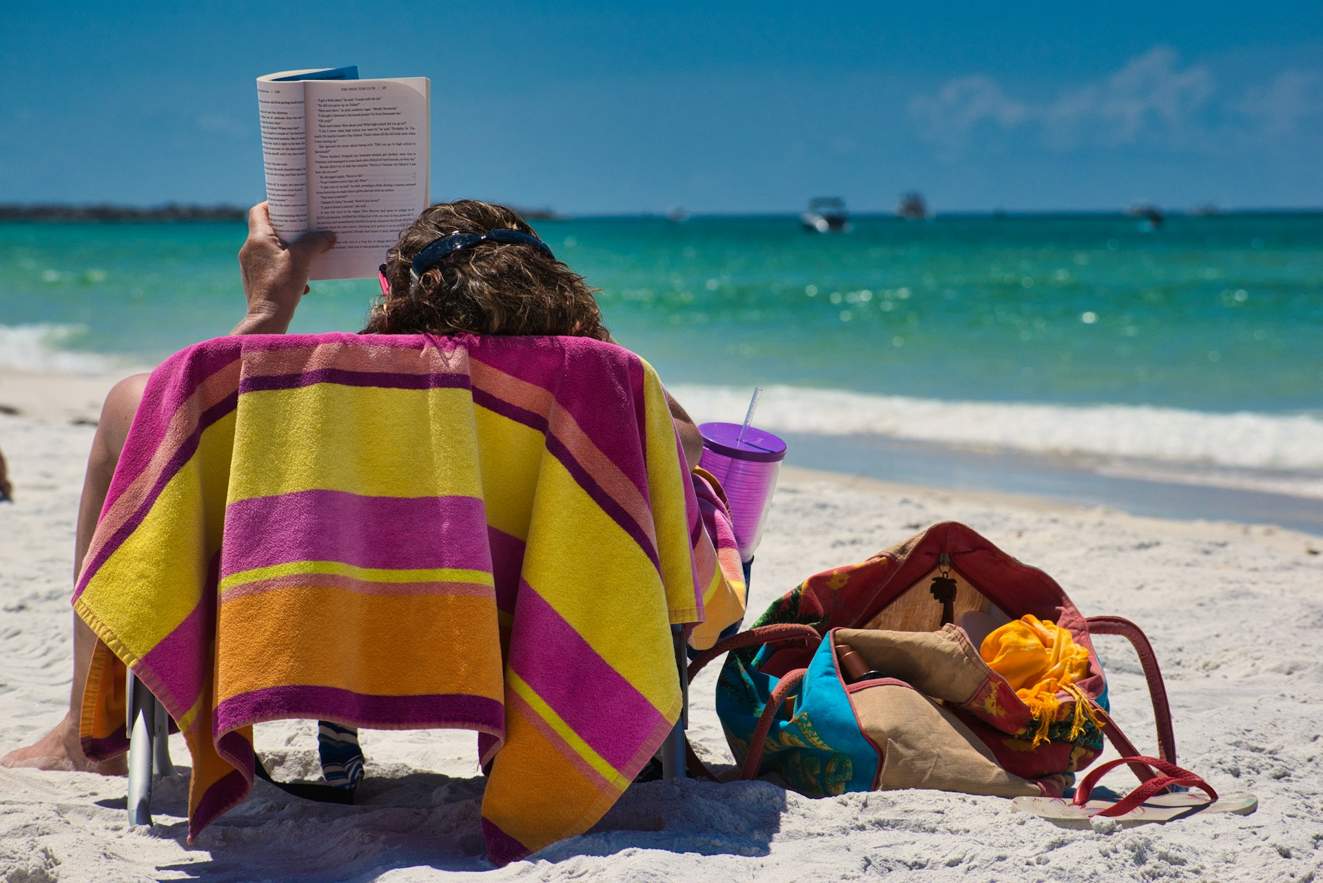 A person at the beach, sitting in a chair, reading a book. Photo by Craig Cameron on Unsplash.