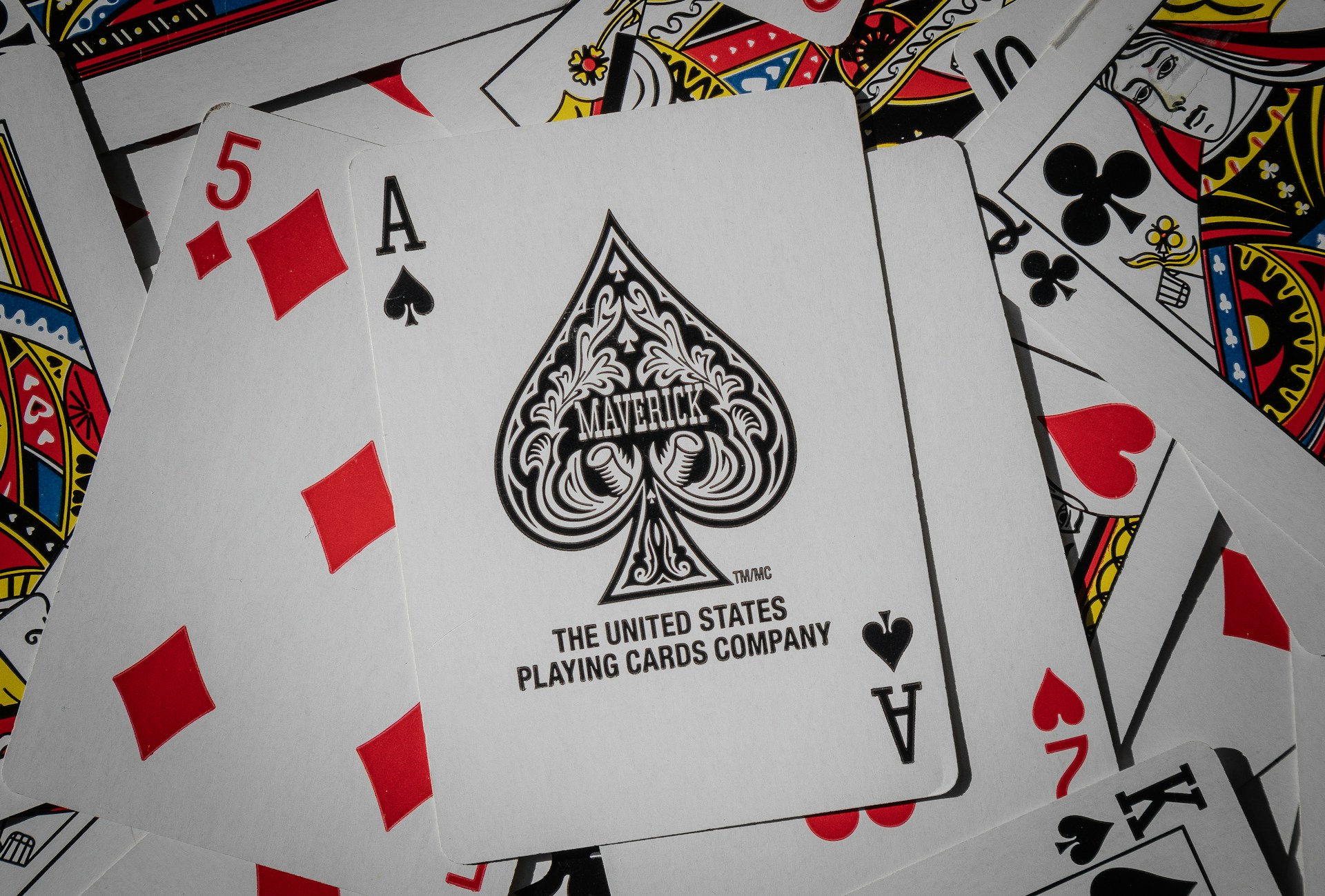 A pile of playing cards on a table.  The ace of spades is front and center.  Photo by Tory Hoffman on Unsplash.