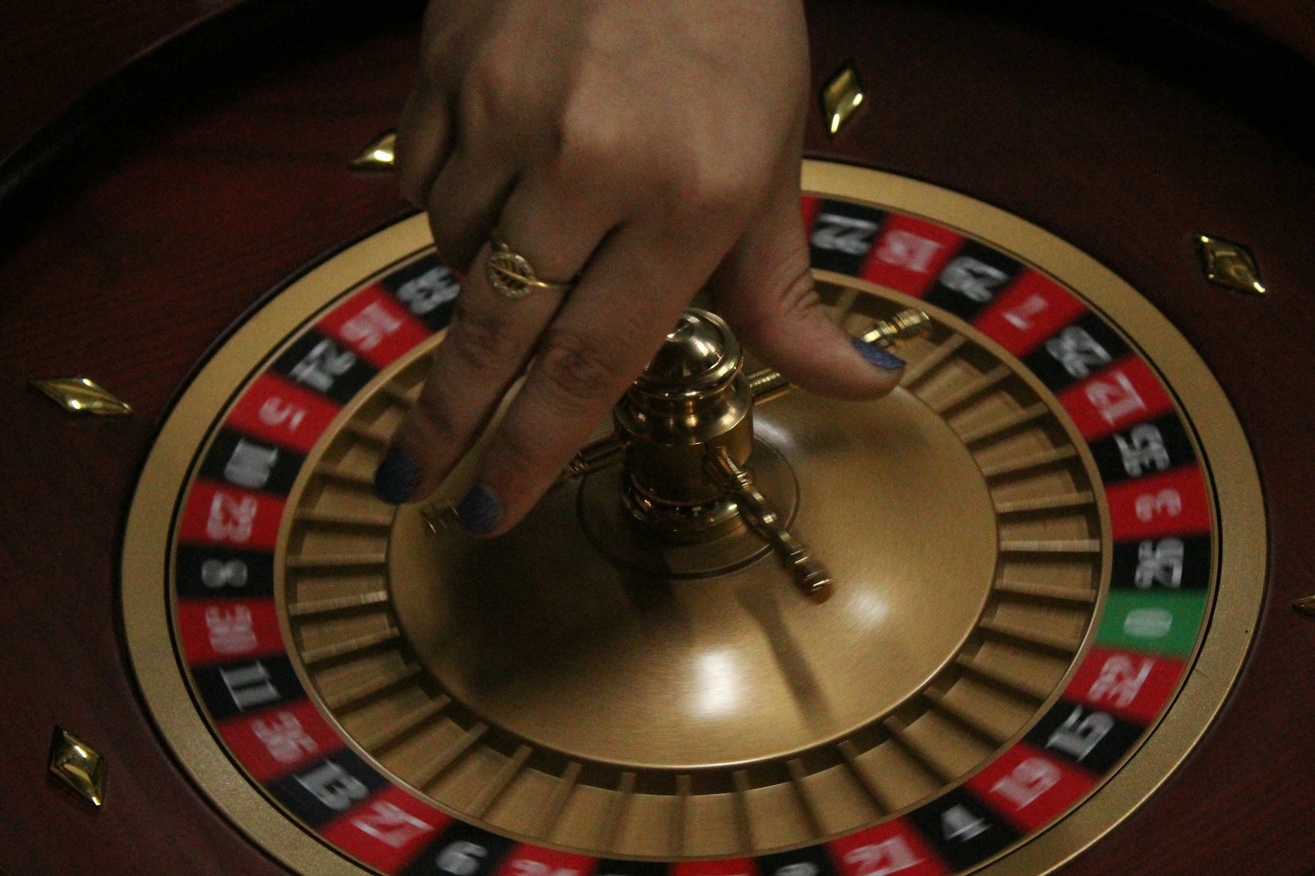 A close-up of a hand spinning a roulette wheel. Photo by Tejas Kotha on Unsplash.