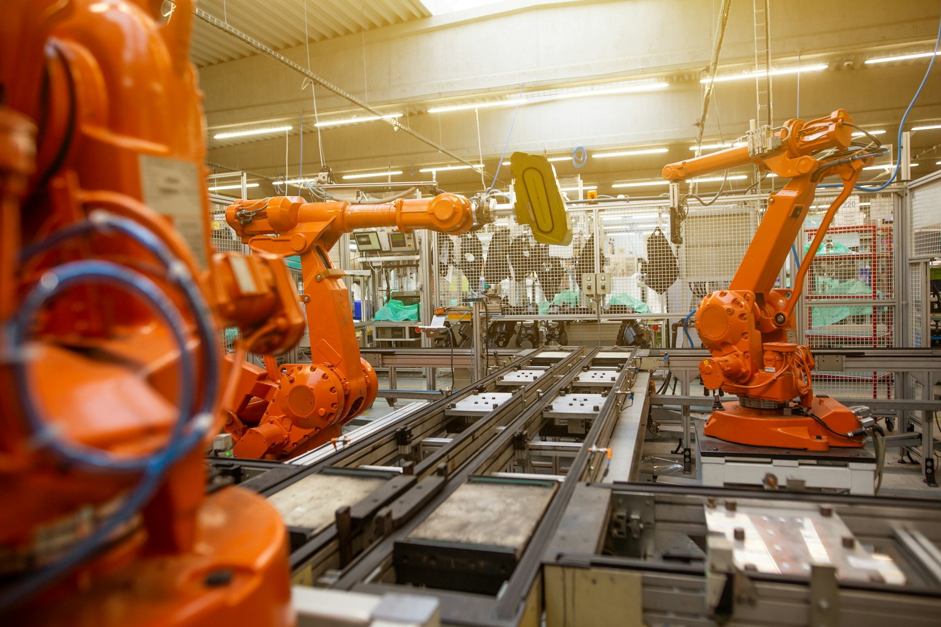Large robotic arms in a factory setting. Photo by Simon Kadula on Unsplash.